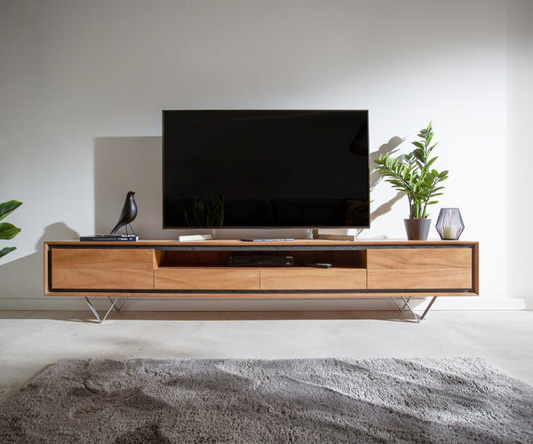 Modern wooden TV stand with two drawers, open shelves, and a metal base, holding a flat-screen TV, décor, and a potted plant.