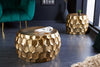 Two gold, honeycomb-patterned drum tables in a modern living room with dark flooring and a green armchair